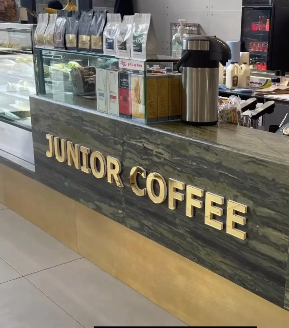 Raised gold-coloured Junior Coffee lettering fitted to a café counter