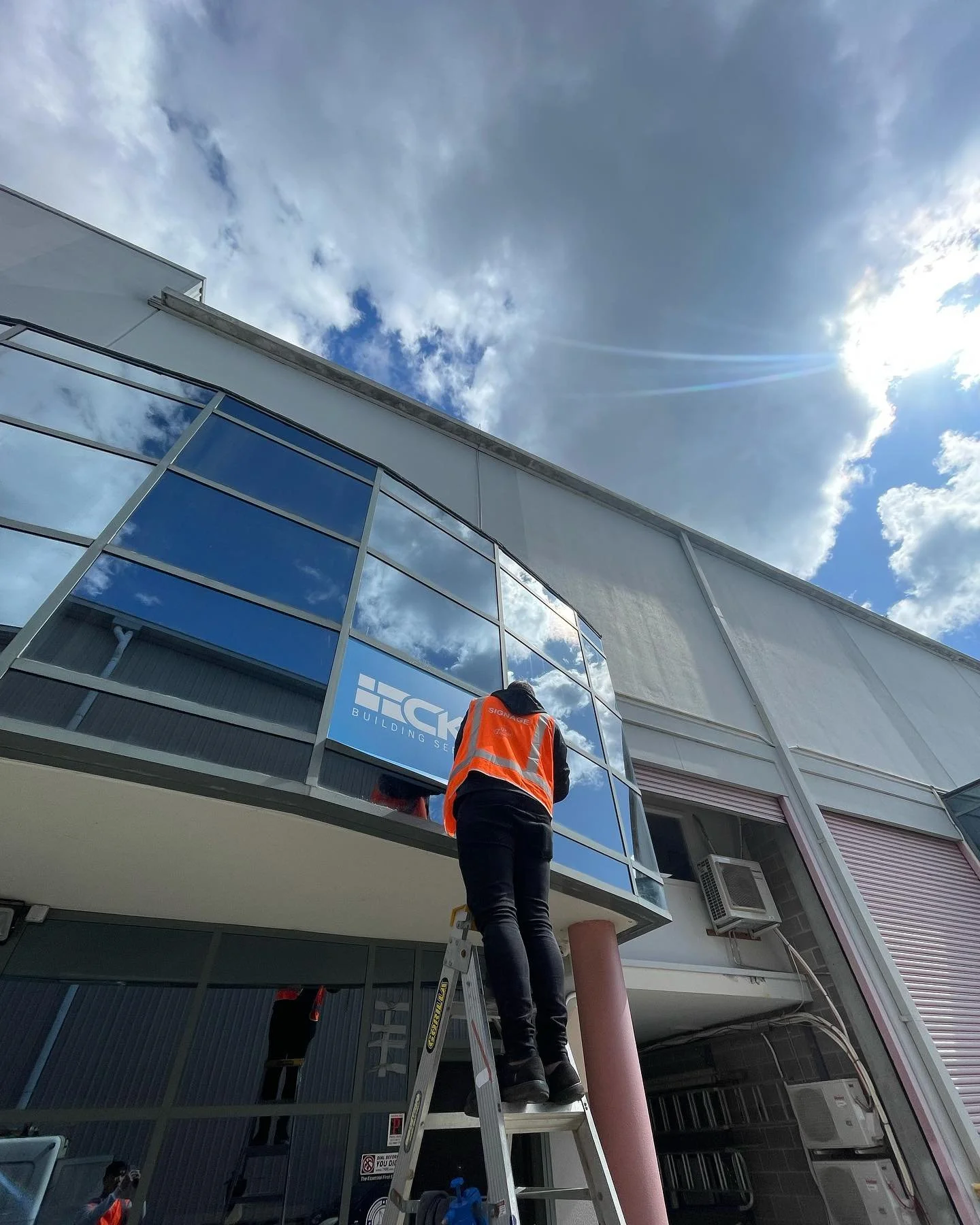 Installer fitting business signage to a commercial building window