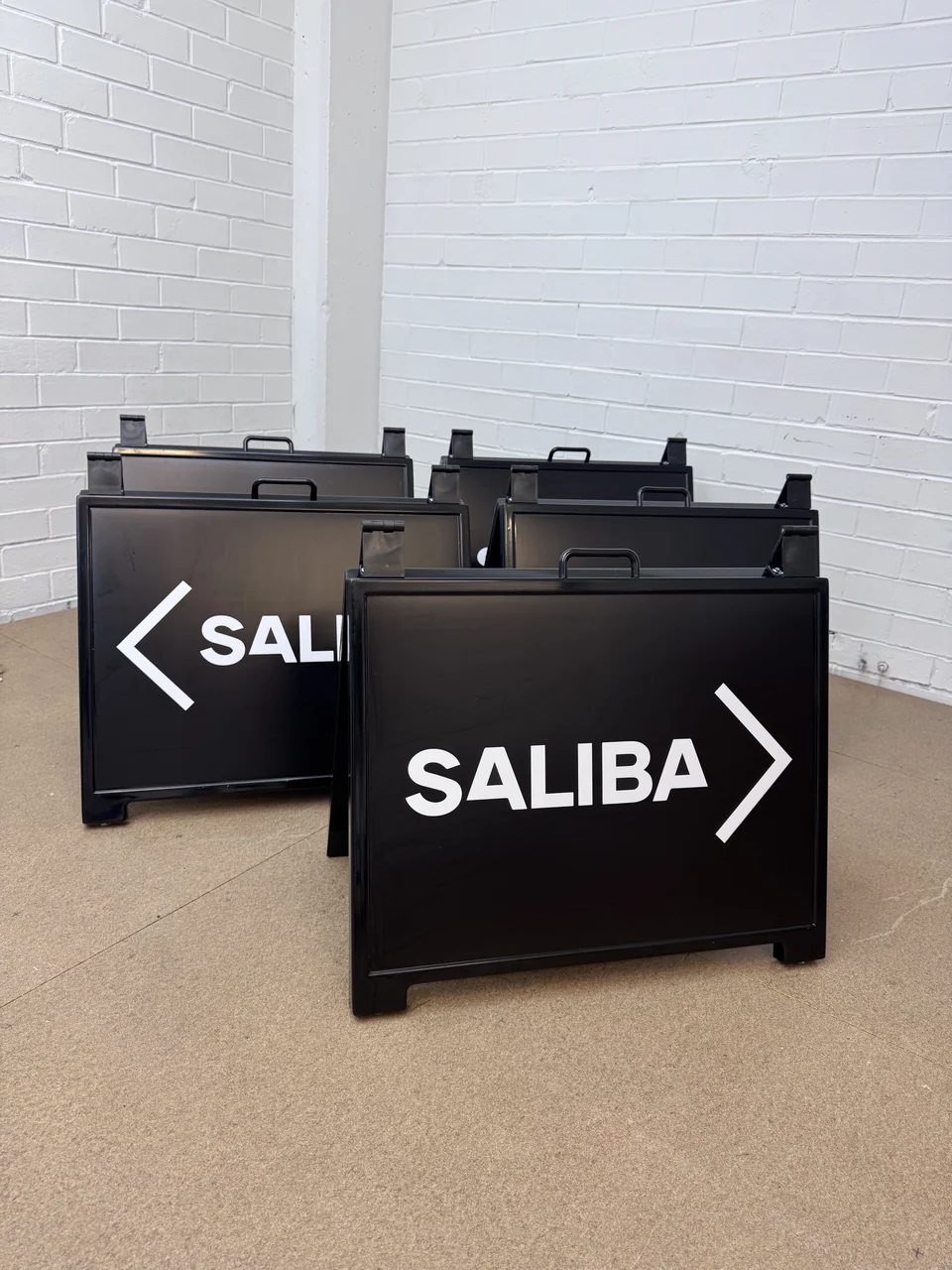 White vinyl lettering and arrows on assembled black Saliba A-frame signs